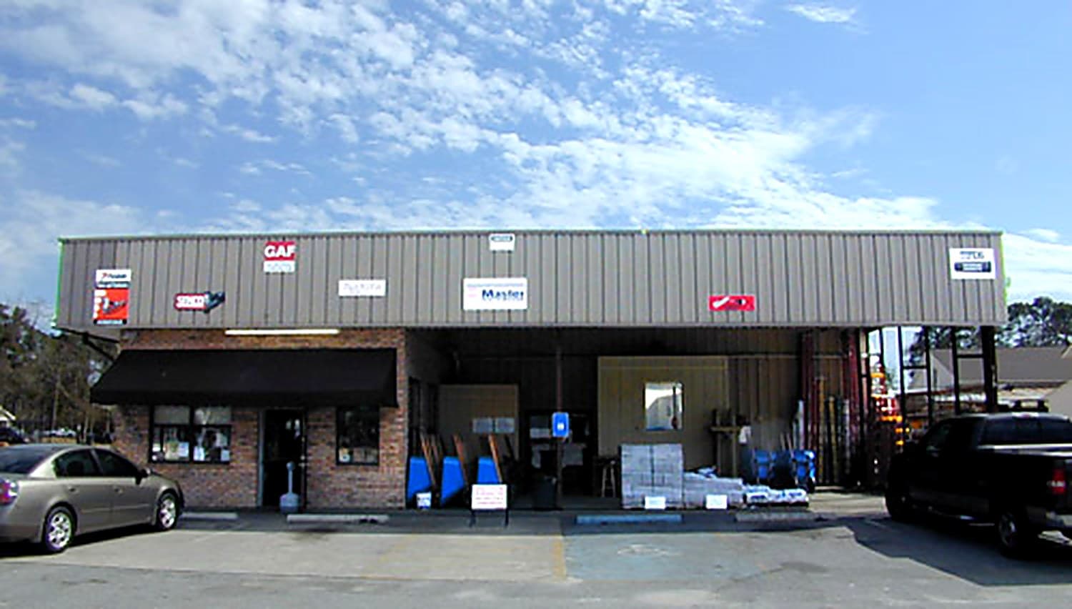 Coastal Hardware storefront on Habersham Street with GAF roofing center sign and parked vehicles out front