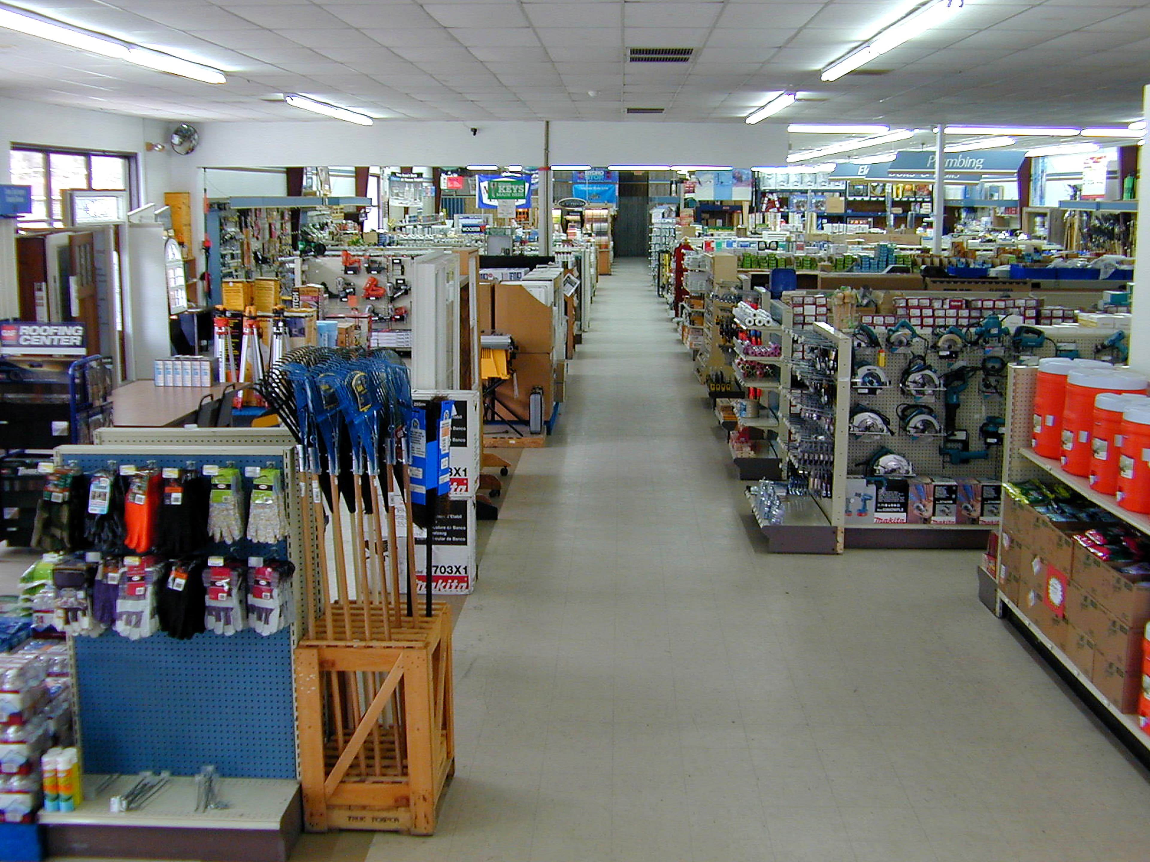 Aisle inside Coastal Hardware showing tool displays and the lumber yard entrance